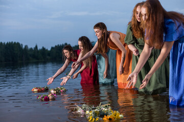 Lovely girls in flower wreaths in nature. Ancient pagan origin celebration concept. Summer solstice...