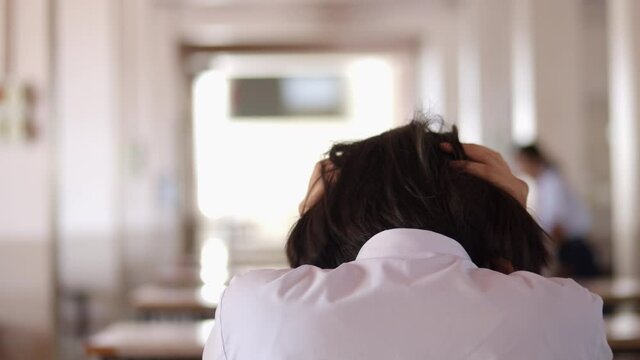 The girl in a white shirt is sitting alone, being so tense that she crunched her head.