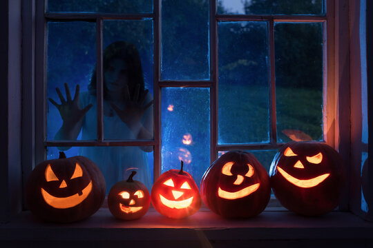 Halloween Pumpins On Windowsill With Ghost Outside  Window