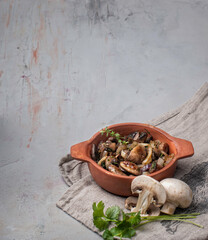 food photography of baked mushrooms with herbs side view in a red ceramic bowl on a gray textured concrete background