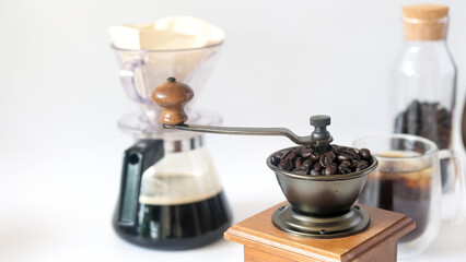 Coffee set, fresh roasted coffee beans in the mill manual coffee grinder and glass bottle black coffee paper drip isolated white background