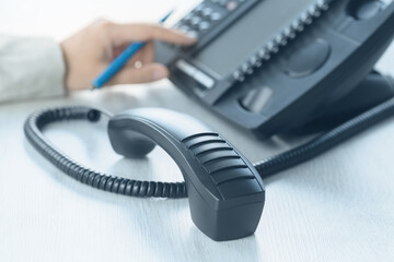 Business and communications. Using voip phone in the office, close up of hand with receiver....
