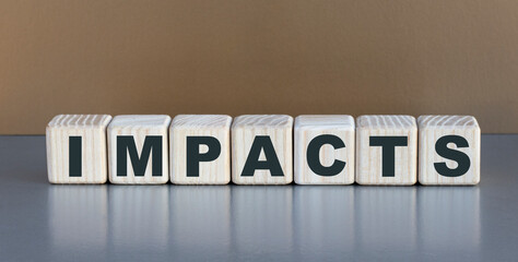 IMPACTS - word on wooden cubes on a beautiful gray background