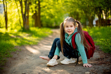 
a child with a backpack puts on sneakers