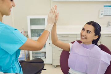 Fototapeta premium Happy woman is happy with the result of dental treatment and gives five to her dentist.