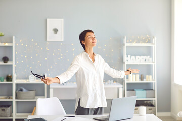 Happy relaxed business woman doing breathing exercises during break in her home office