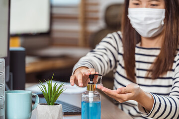 Closeup Asian woman worker hand sanitizer for cleaning her hand when working with computer in Home office when Covid-19 pandemic,Coronavirus outbreak,education and Social distancing,new normal concept