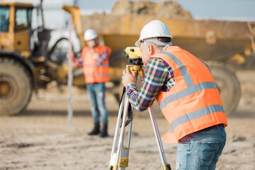 Two road construction workers using measuring device on the field