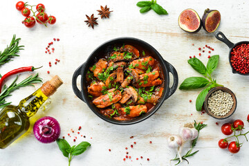 Baked mushrooms with chicken fillet in tomato sauce. In a black stone plate. Top view.