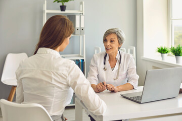 Senior woman doctor therapist consulting young woman patient in medical clinic office