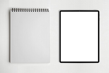 Blank paper notepad and tablet on white table background.