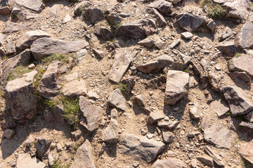 Surface covered with big stones on the ground. The surface of the hiking trail. Top view