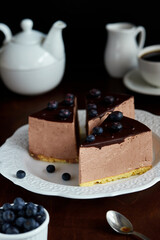 Bird's milk chocolate mousse cake garnished with blueberries on a dark background