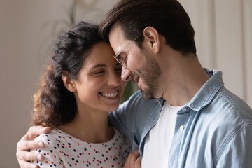 Close up of happy young Caucasian couple embrace sharing romantic tender close intimate moment together. Smiling man and woman hug cuddle enjoy family weekend, show love and care in relationship.