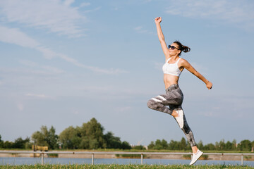 Fototapeta na wymiar Young slim fit woman jump against the sky background
