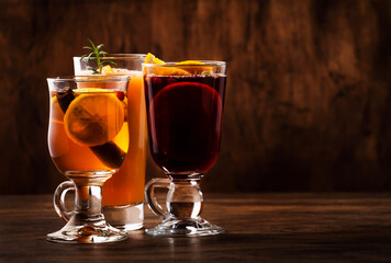 Selection of autumn or winter seasonal alcoholic hot cocktails - mulled wine, glogg, grog, eggnog, warm ginger ale, hot buttered rum, punch, mulled apple cider on wood background, copy s