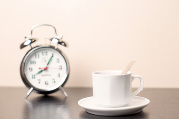 Cup of coffee and alarm clock on the table