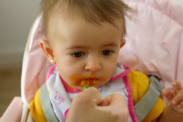 Bebé de frente comiendo potito con jeringa