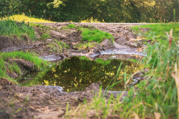 large water puddle on countryside mud road during overflow