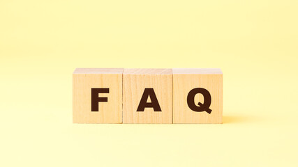 black letters faq on small wooden cubes on bright yellow