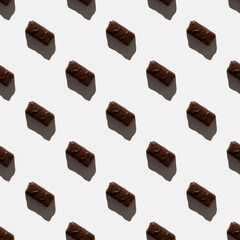 small chocolate bar on a light background. seamless pattern. Background image. Hard shadow. Top view, flat lay