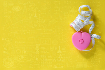 Heart-shaped tape measure on a yellow background,Hand drawn science formulas on chalkboard for background.