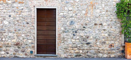 ancient house stone wall with wooden door, panorama banner	