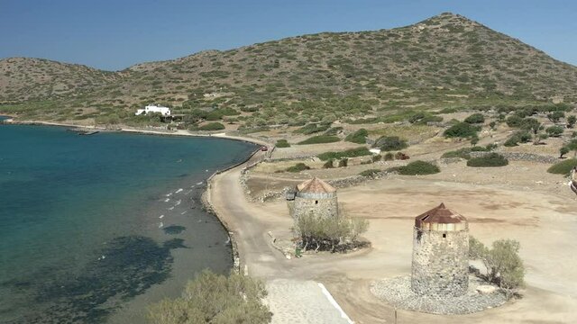 Aerial drone flying low over a dry, yellow Greek landscape in summer (Elounda, Crete)