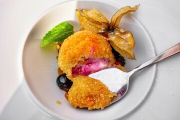 Fried fruit ice cream,grape and physalis on plate with spoon.