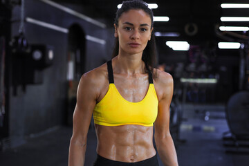 Muscular fit woman standing in gym, looking at camera.