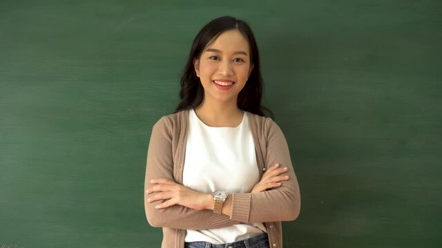 Cheerful young woman with arms folded smiling in school classroom, education, working, school teacher