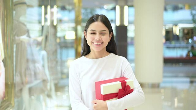 Woman holding a gift box in shopping mall, thanksgiving and Christmas concept..