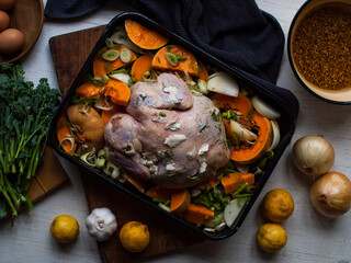 Rustic chicken roast preparation with ingredients on farm table. Natural light.