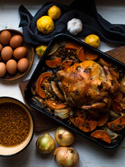 Rustic chicken roast preparation with ingredients on farm table. Natural light.