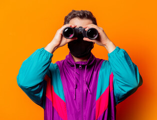 Style man in face mask and 80s tracksuit with binocular