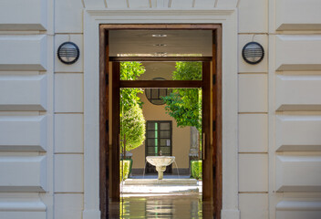 Inner courtyard with a fountain and trees seen from the outside of the building through its open entrance door