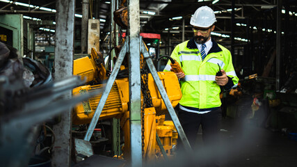 Portrait of successful middle aged Caucasian engineer manager wearing white helmet holding  radio communication check remote control of working machine in dustry