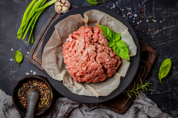  Minced meat in a plate and spices on a black background, top view