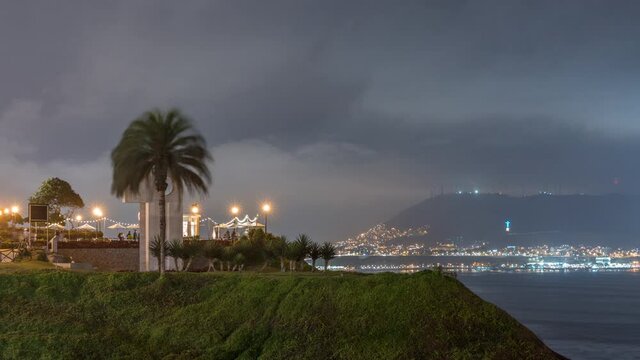 Intihuatana park with panoramic view of Miraflores district and Morro Solar hill on a background day to night timelapse, in Lima, Peru. Palm and caffee with illuminated street lights