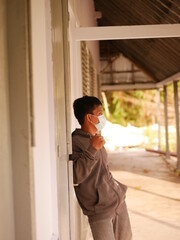 Protrait of an Indonesian young man using a medical mask during the Covid-19 pandemic. Handsome Indonesian guy wears a surgical mask to protect himself from coronavirus