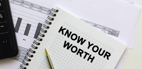 Text on the page of a notepad lying on financial charts on the office desk. Near the calculator. Business concept.