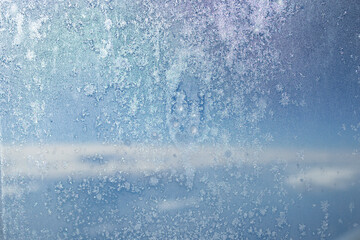 he texture of the frozen window of the plane with visible snowflakes.