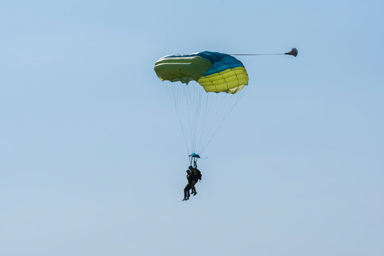 Tandem parachute jump. Silhouette of skydiver flying in blue clear sky. Concepts of extreme sport and adrenaline.