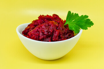 Grated beets. Fresh beet salad in white bowl isolated on yellow background. Healthy food concept, diet, fresh vegetables, vitamins and liver recovery.