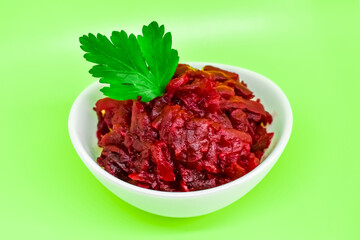 Grated beets. Fresh beet salad in a white bowl isolated on a light green background. The concept of healthy food, diet, fresh vegetables, vitamins and liver recovery.