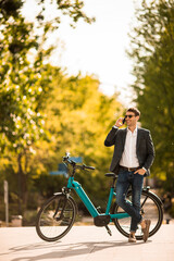 Obraz premium Young businessman on the ebike using mobile phone