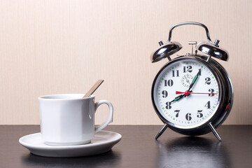 Fototapeta na wymiar Cup of coffee and alarm clock on the table