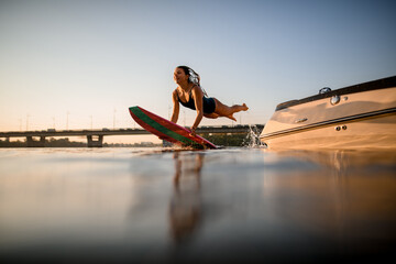 handsome woman with surf style wakeboard in her hands flies over the water