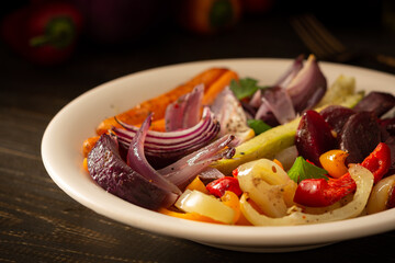 Stewed vegetables in a plate, carrots with garlic and red onions,zucchini with bell pepper and beetroot, sweet and hot peppers and spices
