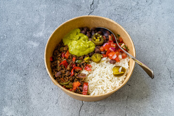 Take Away Traditional Mexican Tex-Mex Food with Minced Meat, Basmati Rice, Chicken and Guacamole Sauce in  Take Out Plastic Bowl.